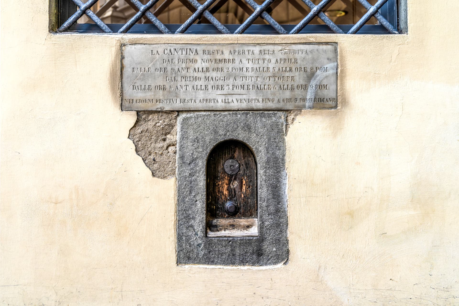 Buchetta del vino histórica com placa em mármore anunciando horários da cantina